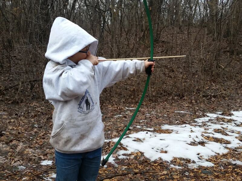 Child practicing archery outdoors